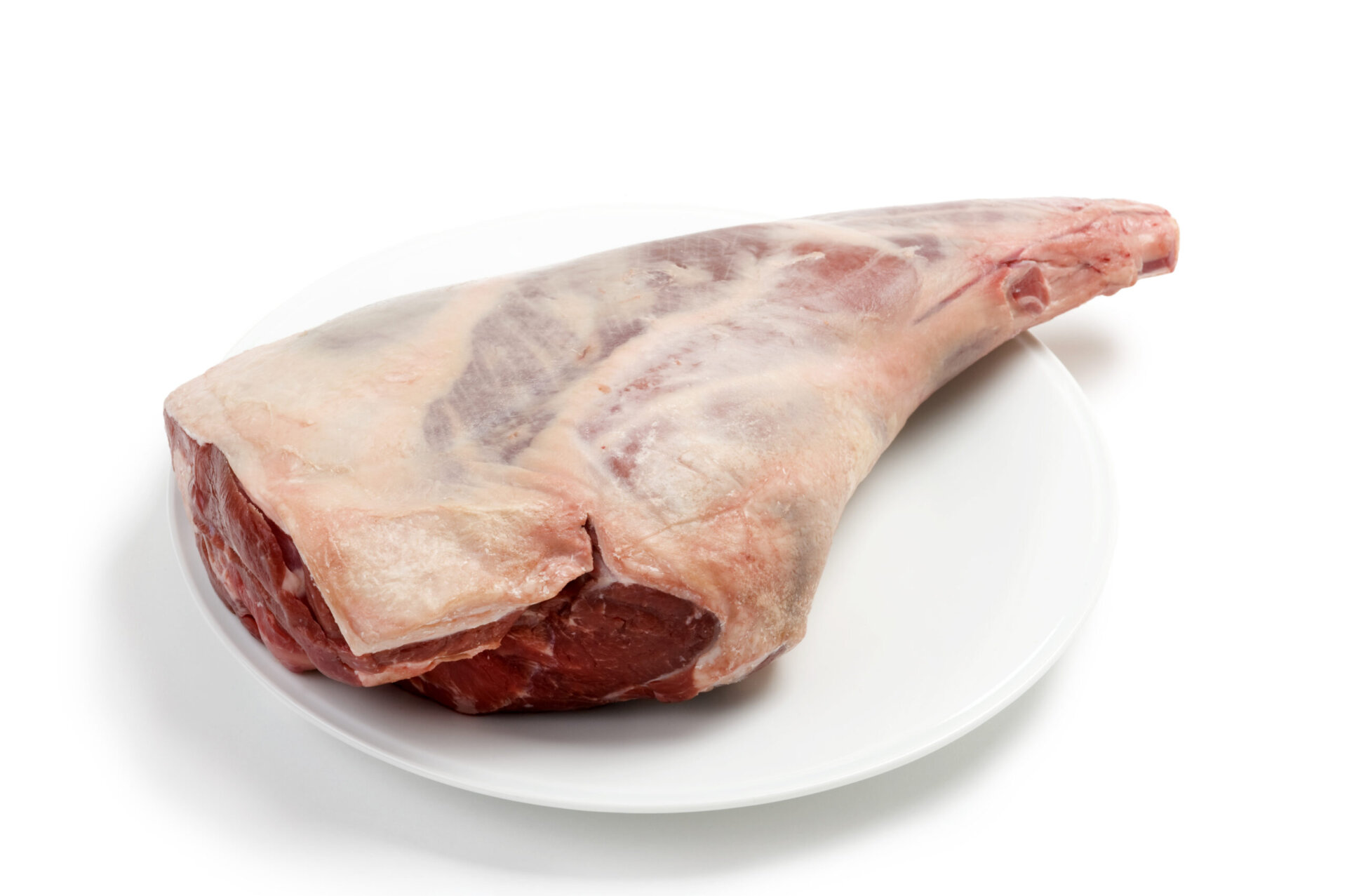 Large raw leg of lamb on a white plate